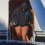 Lizzo shows off her long legs in a pair of bike shorts as she steps off her private jet in Sydney after performing at Splendour in the Grass