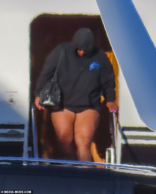 Lizzo shows off her long legs in a pair of bike shorts as she steps off her private jet in Sydney after performing at Splendour in the Grass