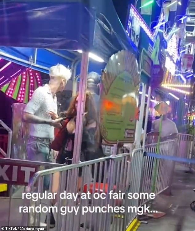 Megan Fox gets slammed into barrier as passer-by ‘takes a SWING’ at Machine Gun Kelly during night out at the fair in explosive clip